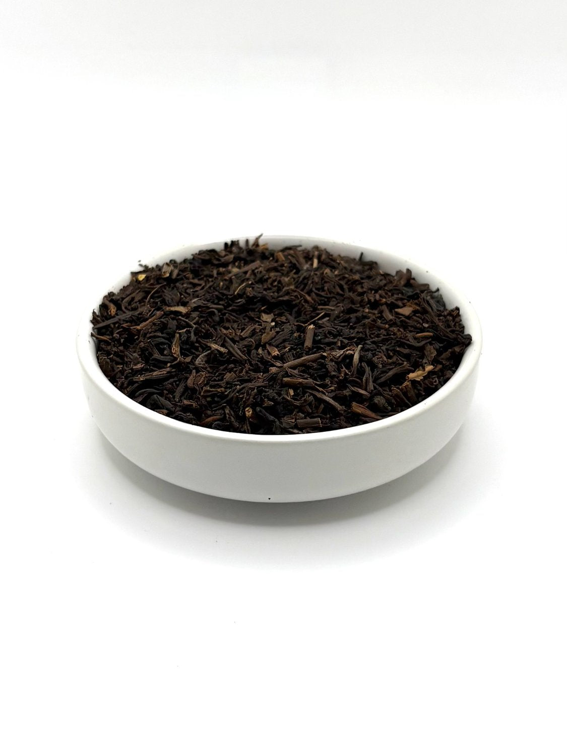 Decaf Earl Grey black tea leaves in ceramic bowl, angled view