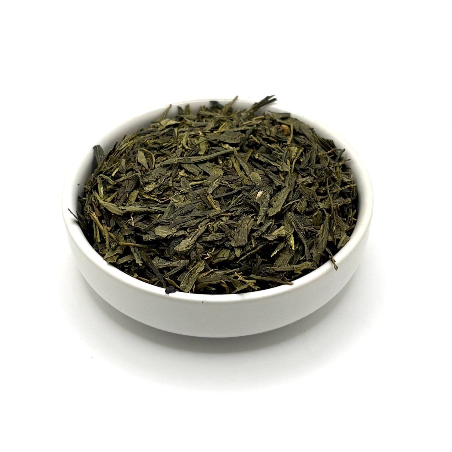 Angled view of flat-cut green Sencha tea leaves in a bowl, emphasizing their crisp texture and color